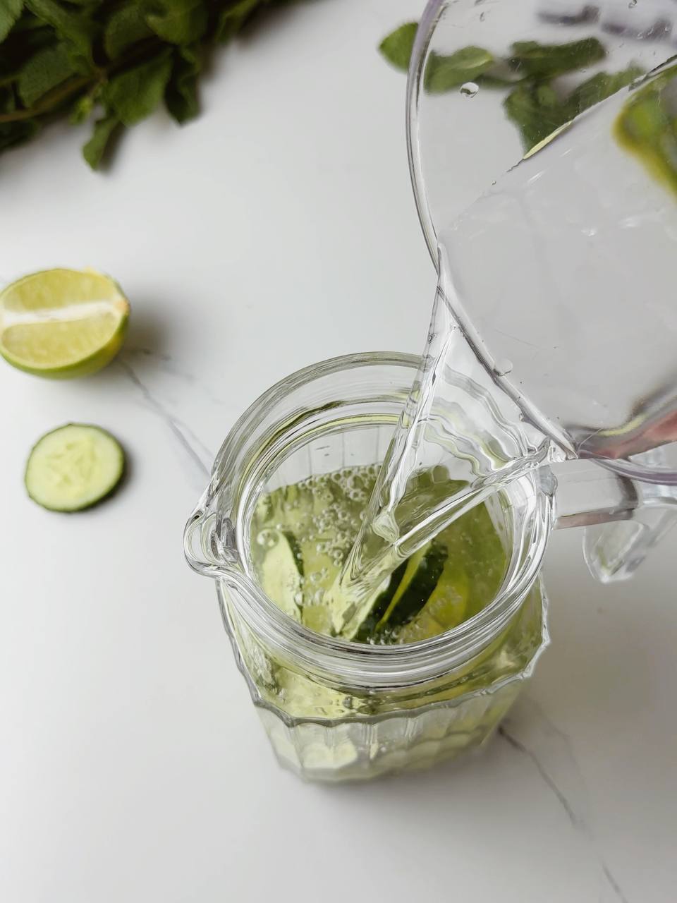 Pouring cold water over cucumber and lime slices