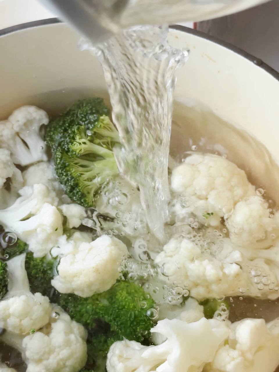 Boiling water poured over broccoli and cauliflower florets to soften.