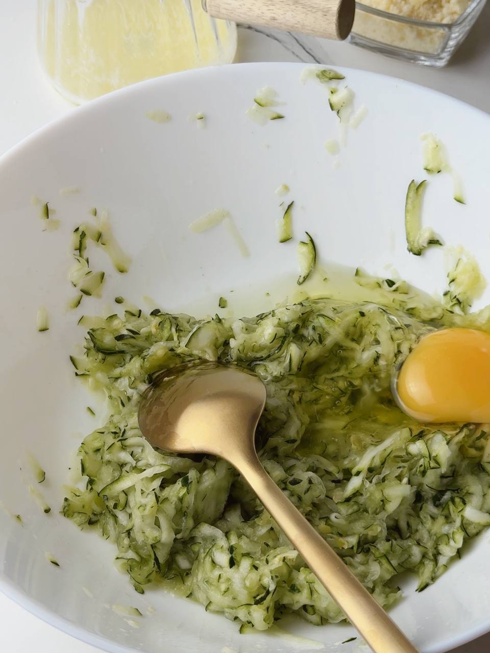 Cracked egg added to grated zucchini mixture for savory waffle batter.