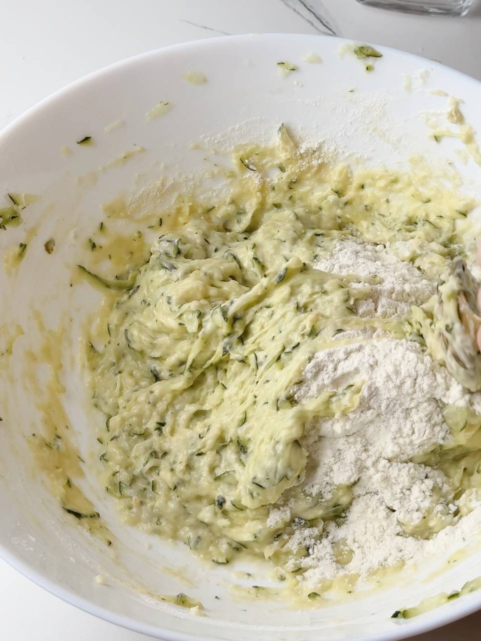 Flour being mixed into the zucchini and egg mixture for waffle batter.