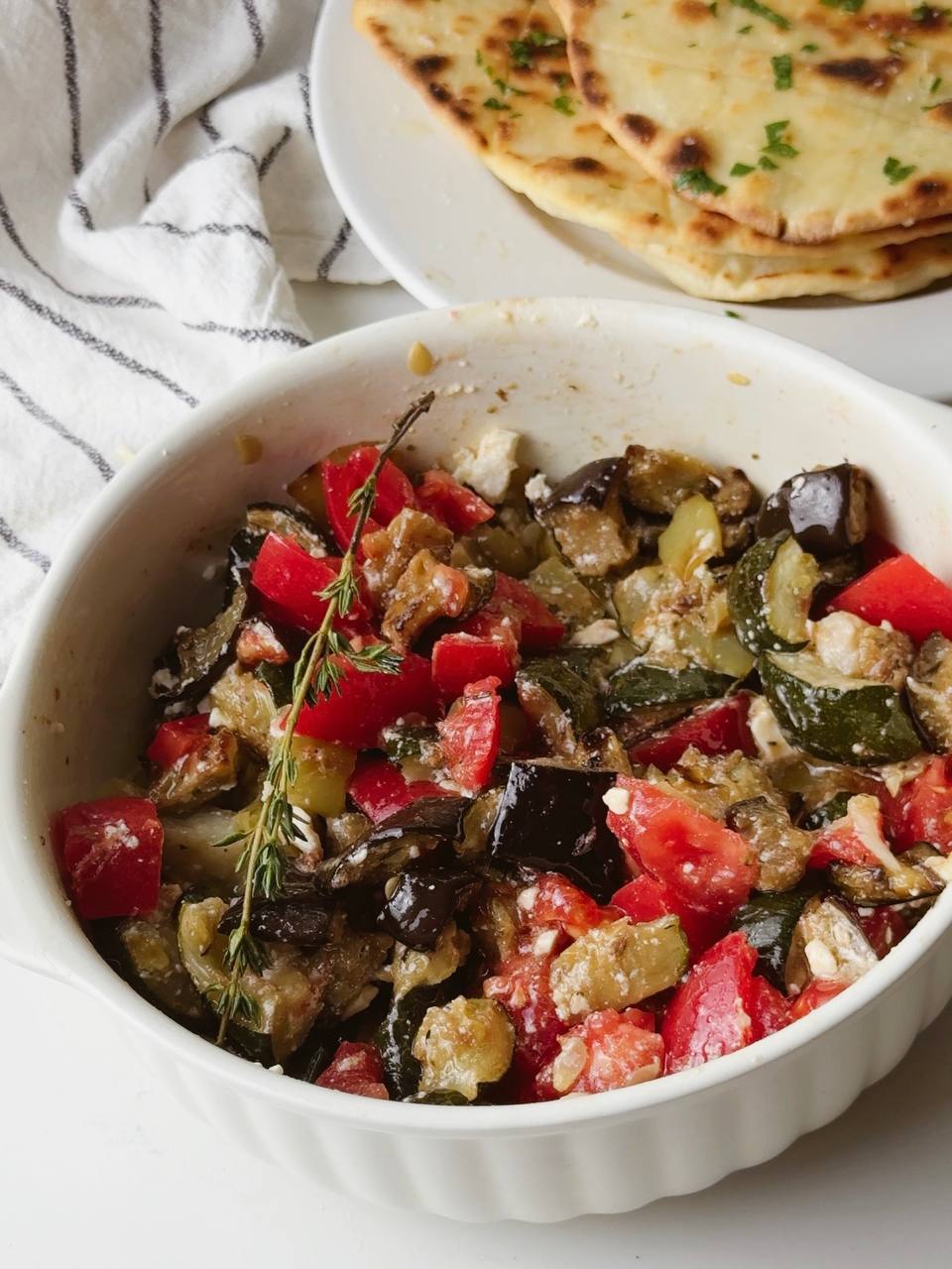 Final dish of oven-roasted vegetables with feta, tomato, and olive oil, ready to serve.