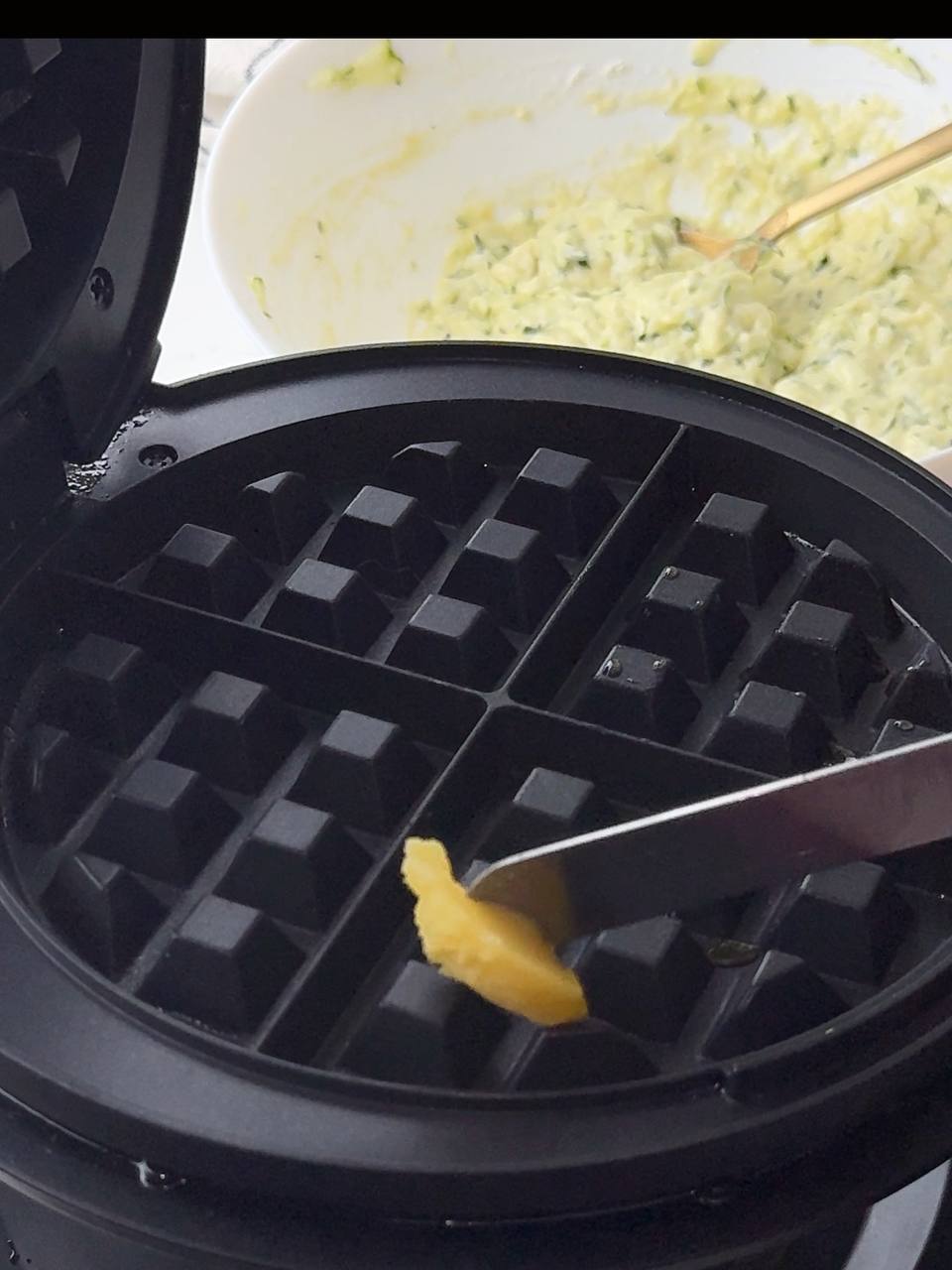 Brushing melted butter onto a waffle maker before cooking.