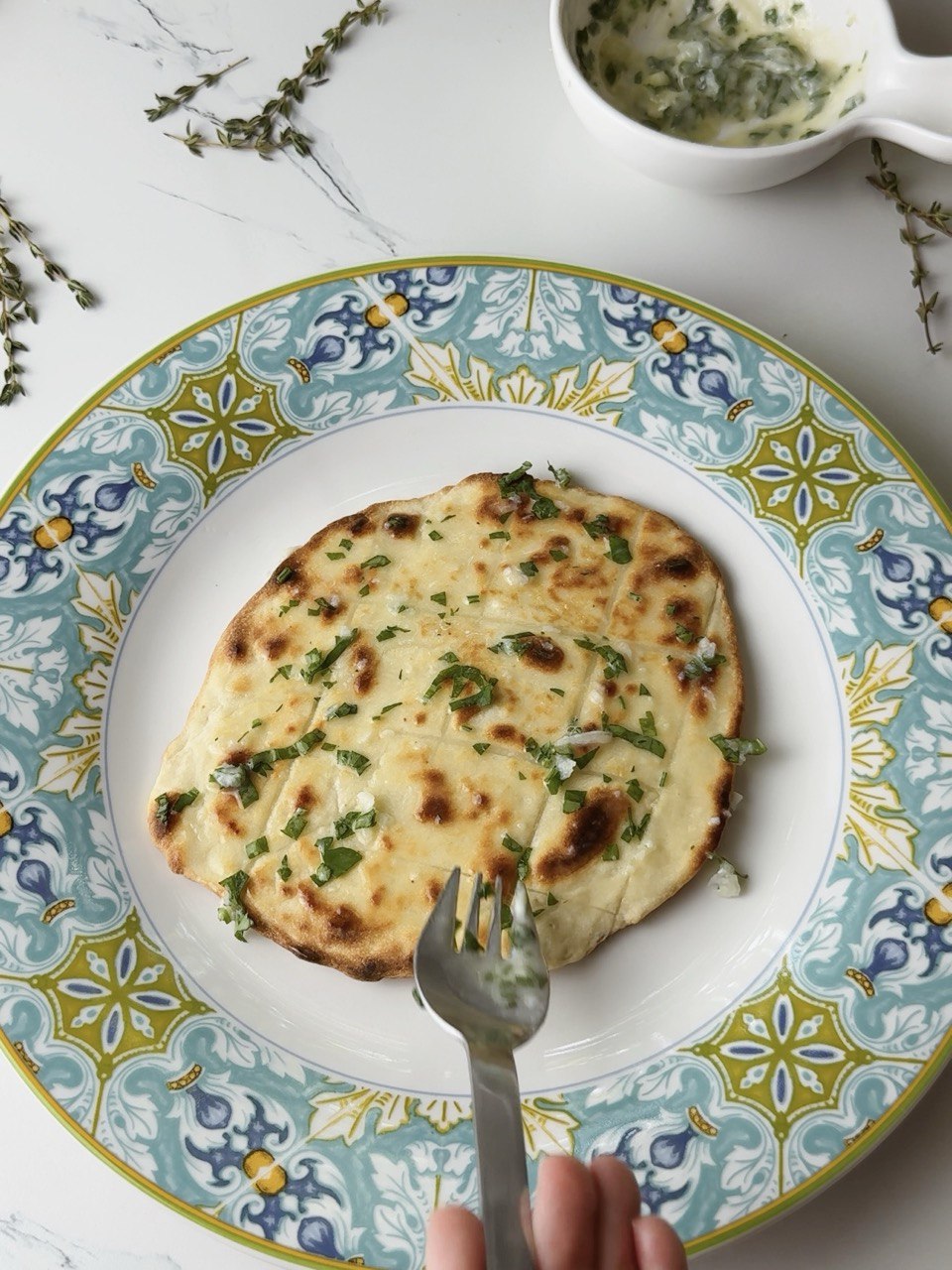 Warm flatbread being brushed with melted garlic butter and parsley.