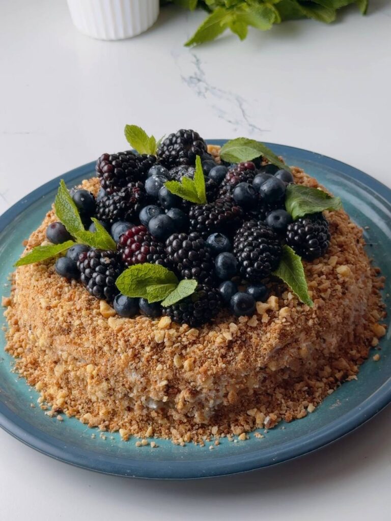 Finished condensed milk layer cake decorated with berries and mint.