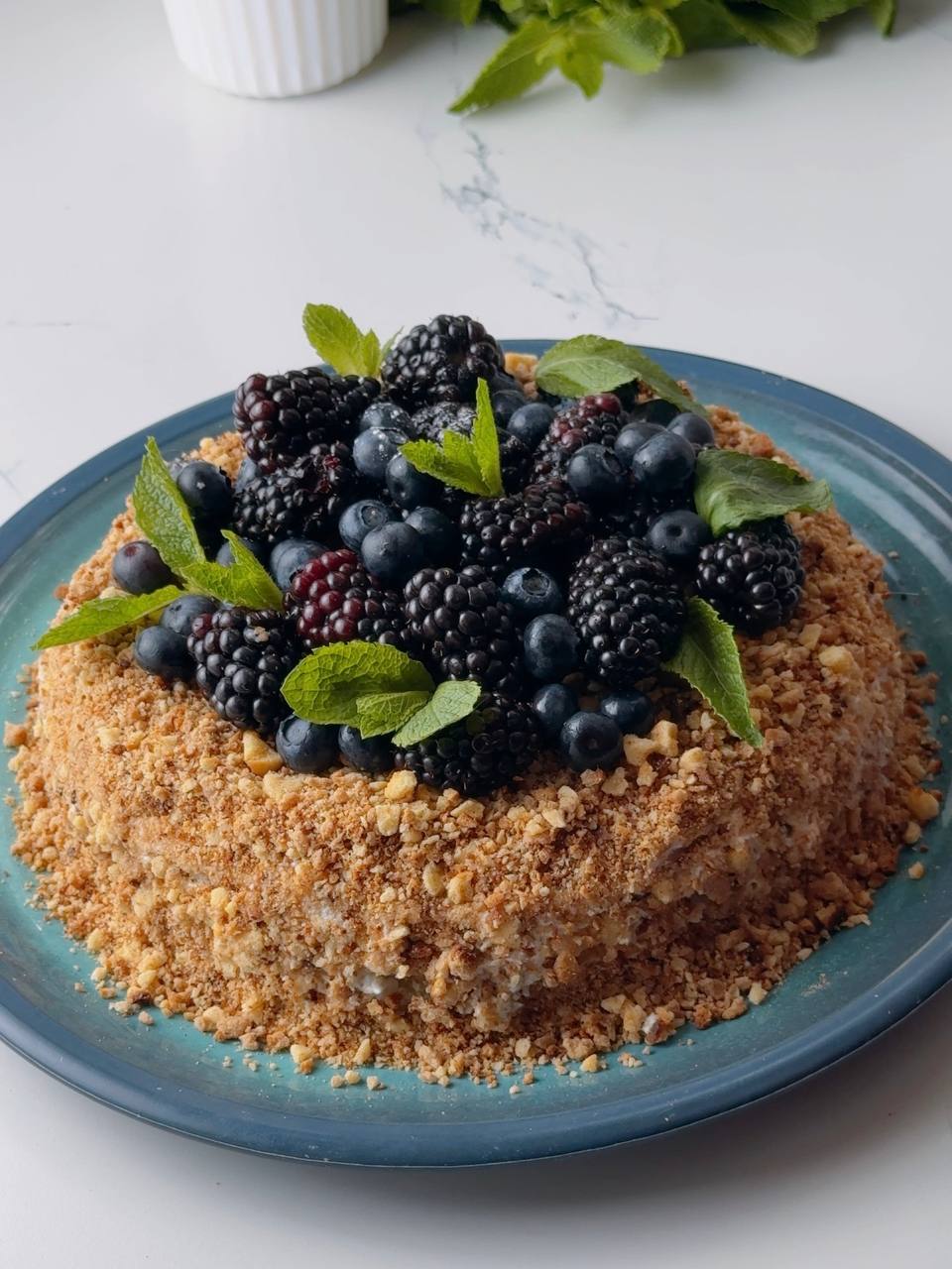 Finished condensed milk layer cake decorated with berries and mint.