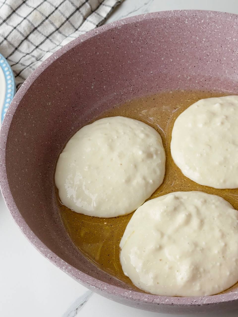 Cottage cheese pancakes cooking on a pan in perfect rounds.