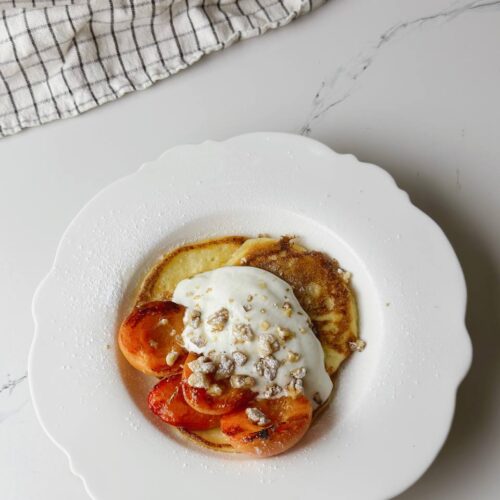 Top view of a breakfast plate with cottage cheese pancakes and grilled apricots.