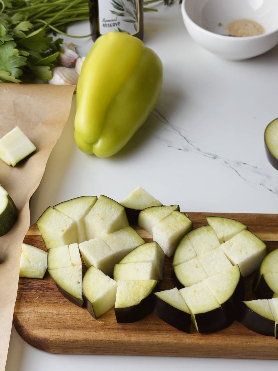 Diced eggplant (aubergine) on a cutting board, ready to be roasted.