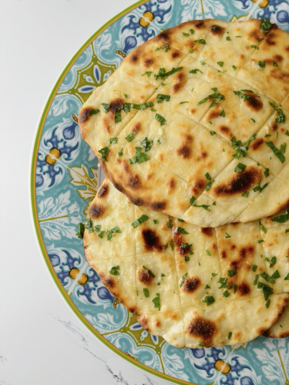 Final garlic flatbread served on a blue plate, ready to eat