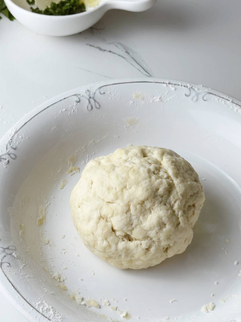 Smooth ball of flatbread dough resting on a floured surface.