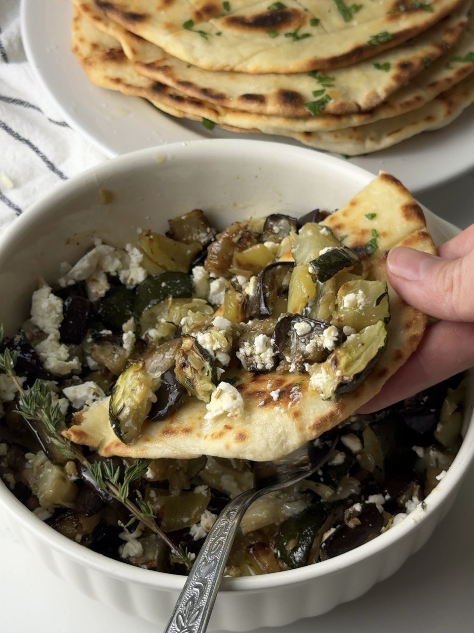 Garlic flatbread served with one-tray baked vegetables and feta – a cozy Mediterranean meal idea.