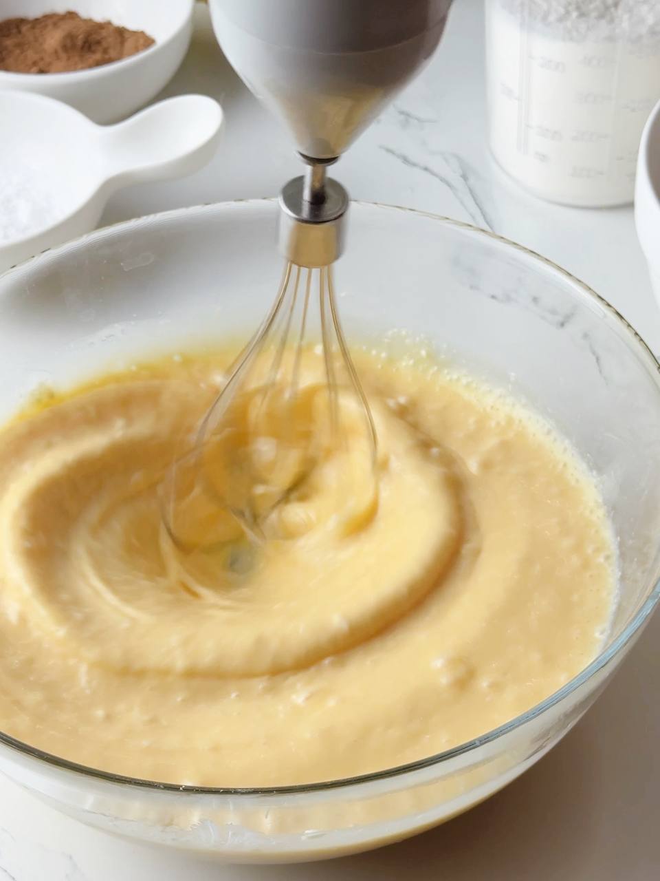 Mixing the condensed milk cake batter with a hand mixer until smooth.
