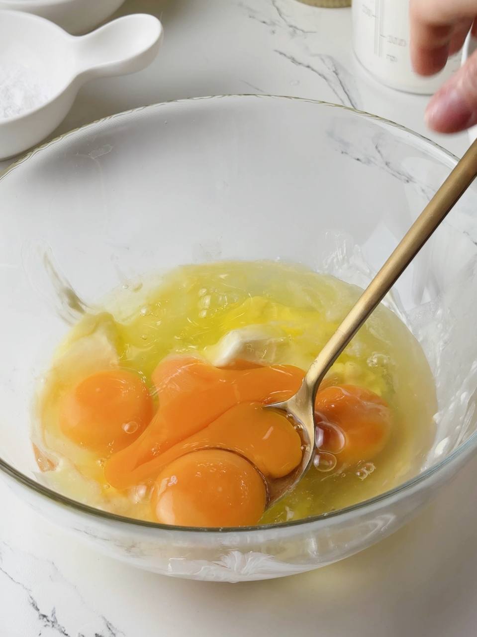 Eggs and butter being mixed in a bowl with a spoon.