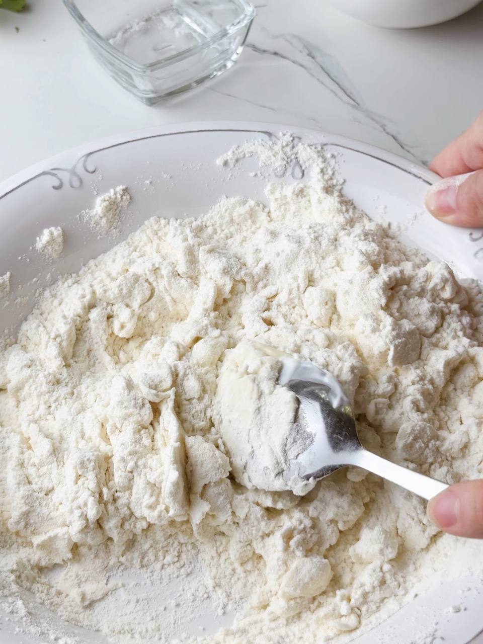 Stirring flatbread dough in a bowl using a spoon.