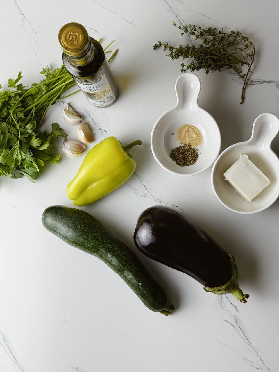 Ingredients for one-tray baked vegetables with feta, including zucchini, eggplant, bell pepper, garlic, herbs, and olive oil.