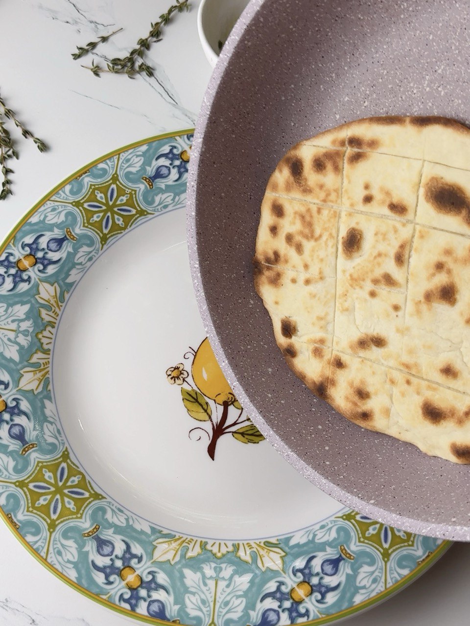 Freshly cooked flatbread being transferred from pan to plate.