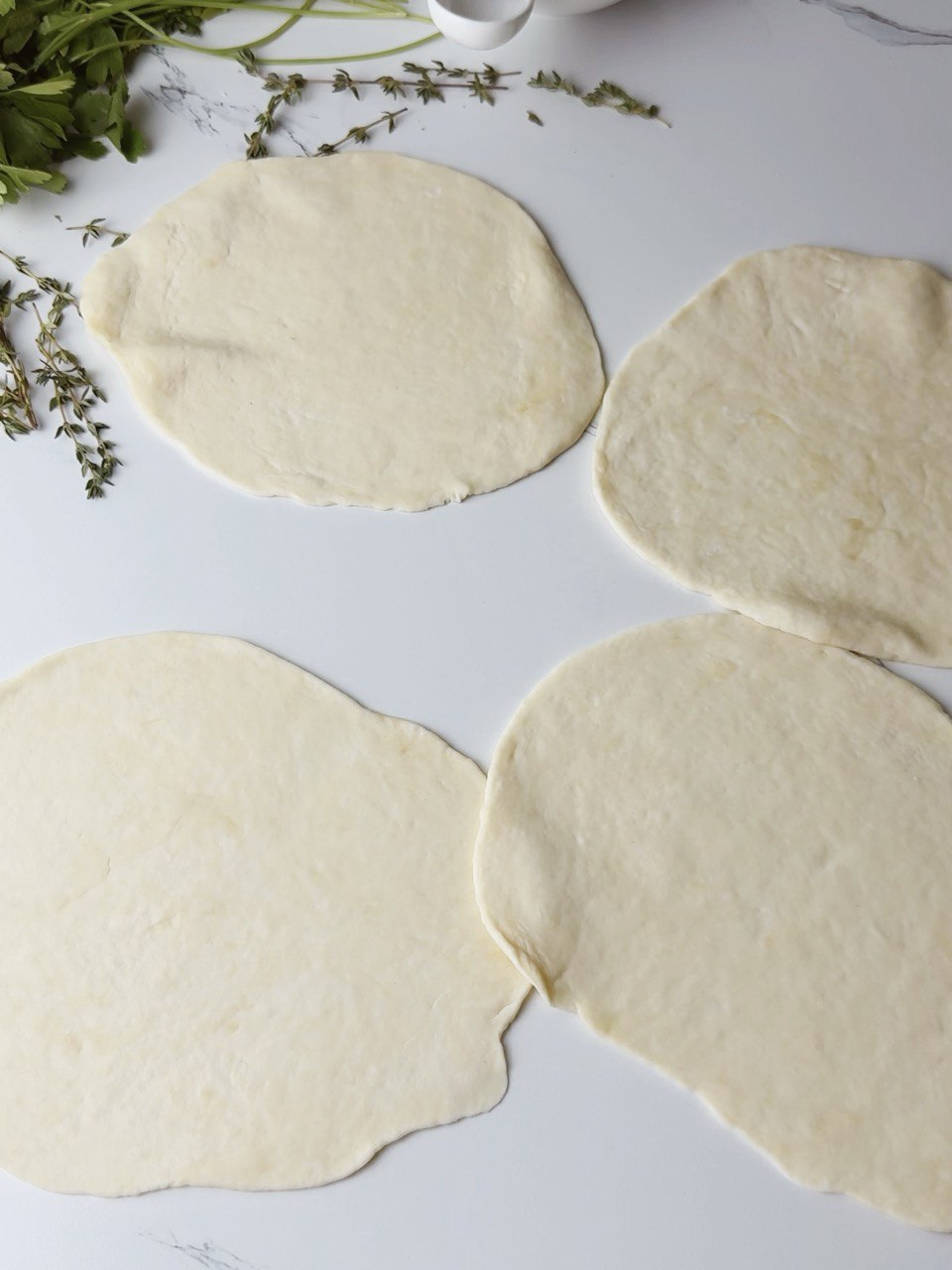 Rolled-out flatbread dough disk on a floured surface.