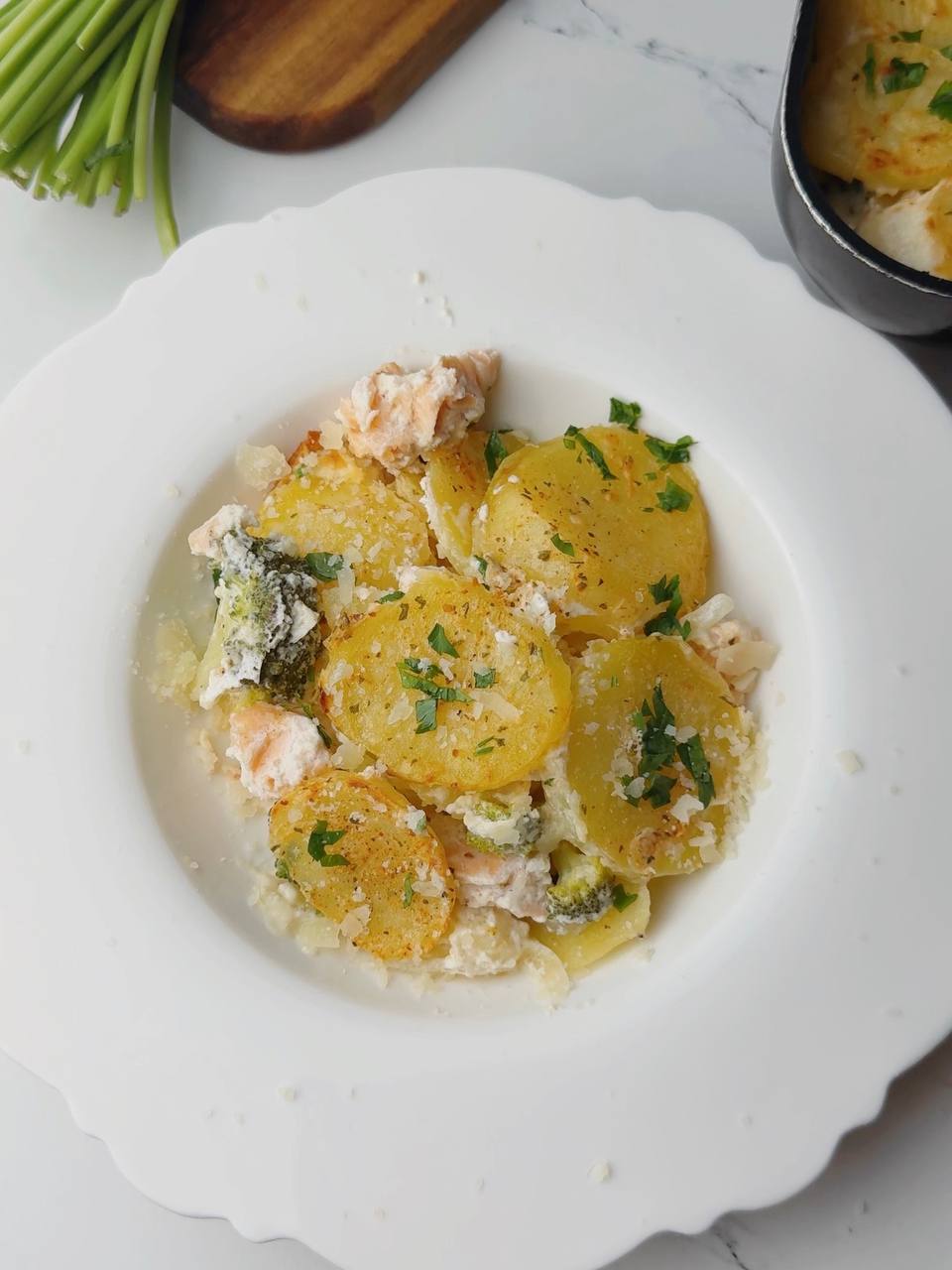 Plated serving of creamy baked salmon with potato and broccoli, topped with Biraghi cheese