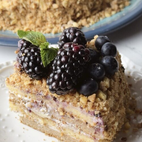 A slice of condensed milk layer cake served on a plate, showing the chocolate and vanilla layers with cream.