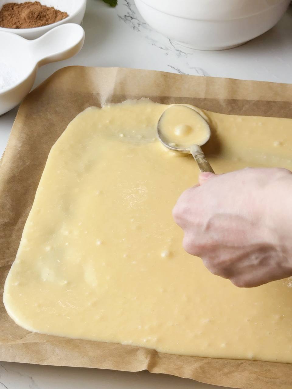 Half of the cake batter spread evenly onto a parchment-lined baking tray