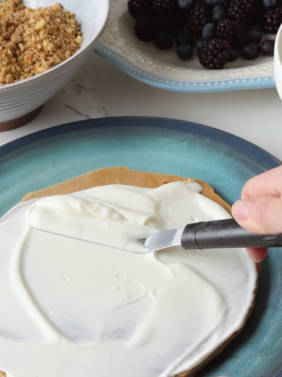 A layer of cream being spread over the sponge for cake assembly.