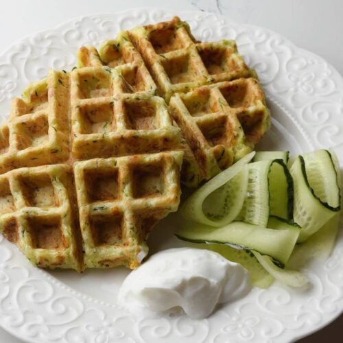 Crispy zucchini waffle served with Greek yogurt and cucumber slices on the side