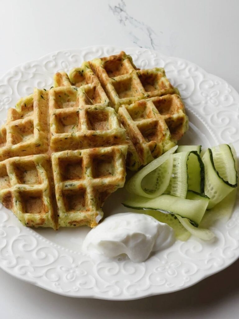 Crispy zucchini waffle served with Greek yogurt and cucumber slices on the side