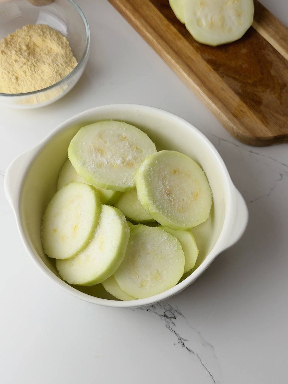 Sliced zucchini in a bowl sprinkled with salt to release moisture.
