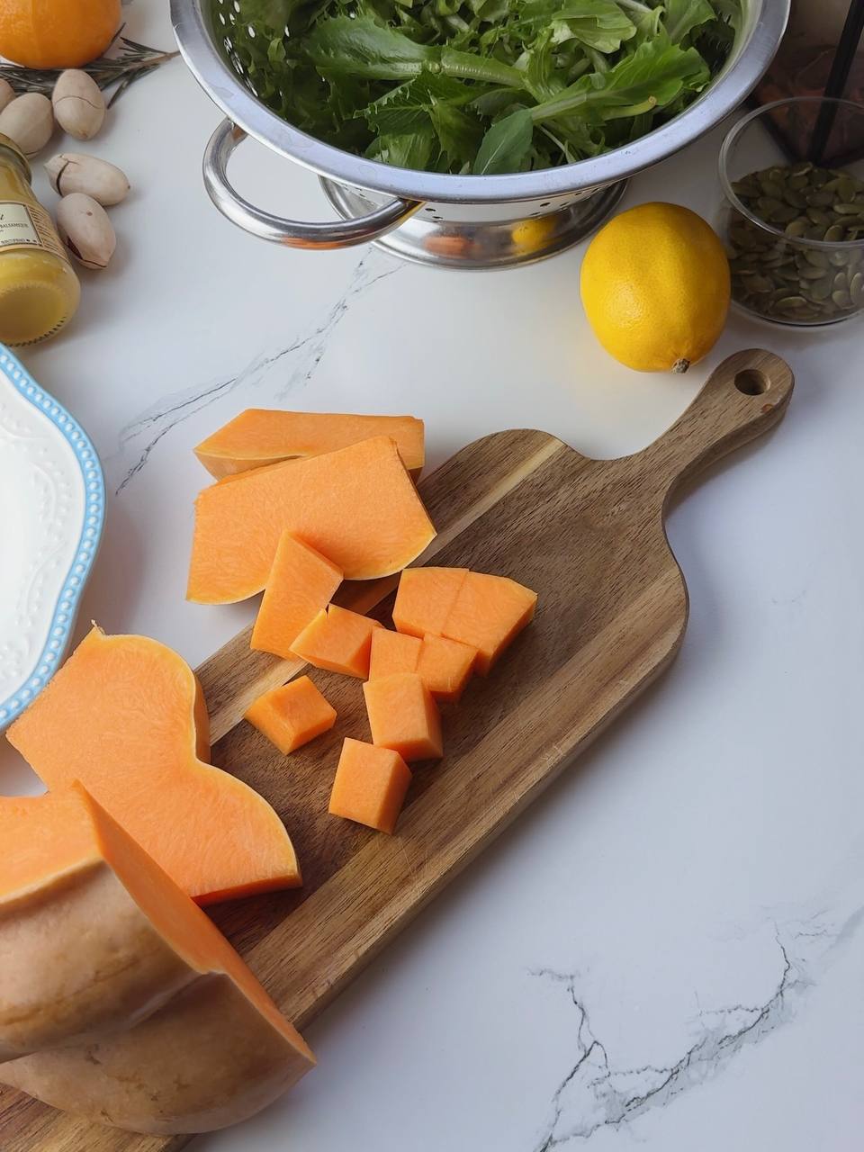 Cut pumpkin cubes on wooden cutting board ready for baked pumpkin salad