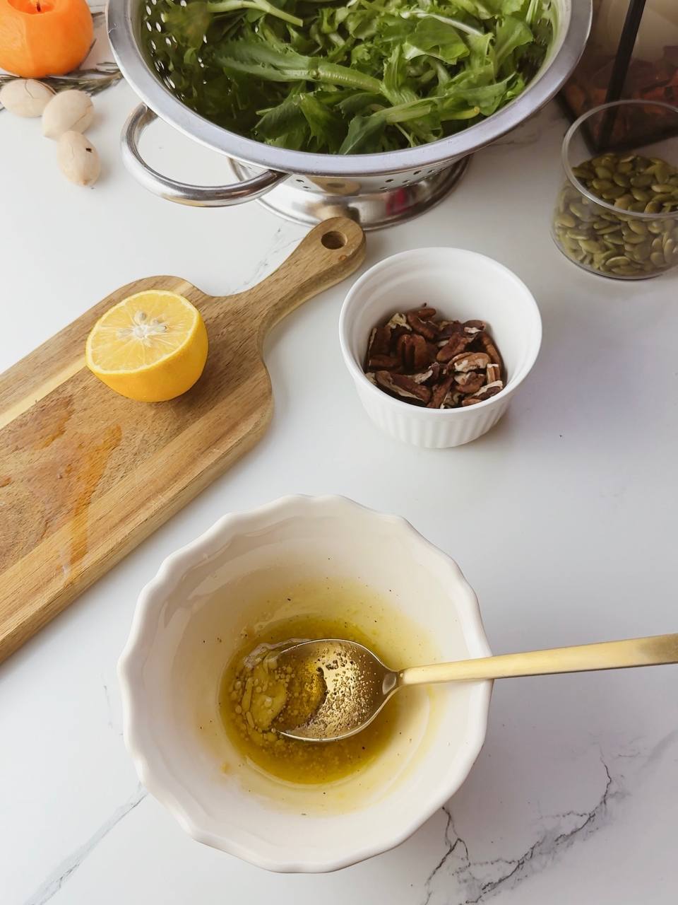 Whisking olive oil, lemon juice, and Dijon mustard to make dressing for baked pumpkin salad