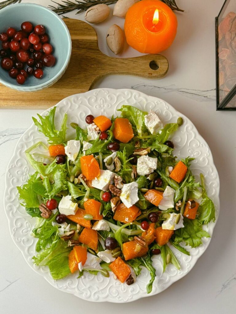 Beautifully plated baked pumpkin salad with feta, cranberries, pecans, and pumpkin seeds