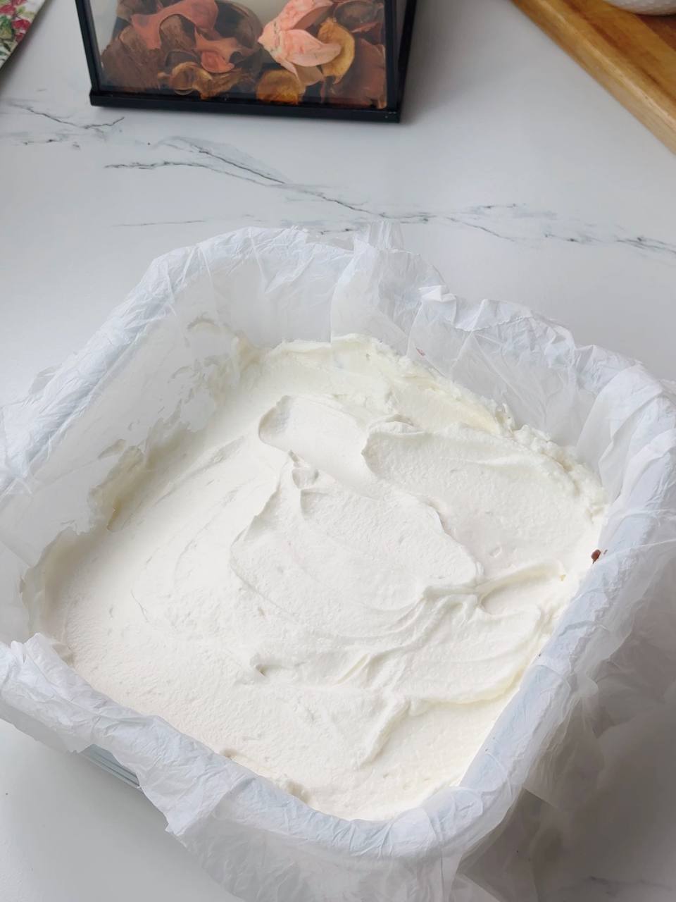 Spreading cream cheese layer over brownie with cherries