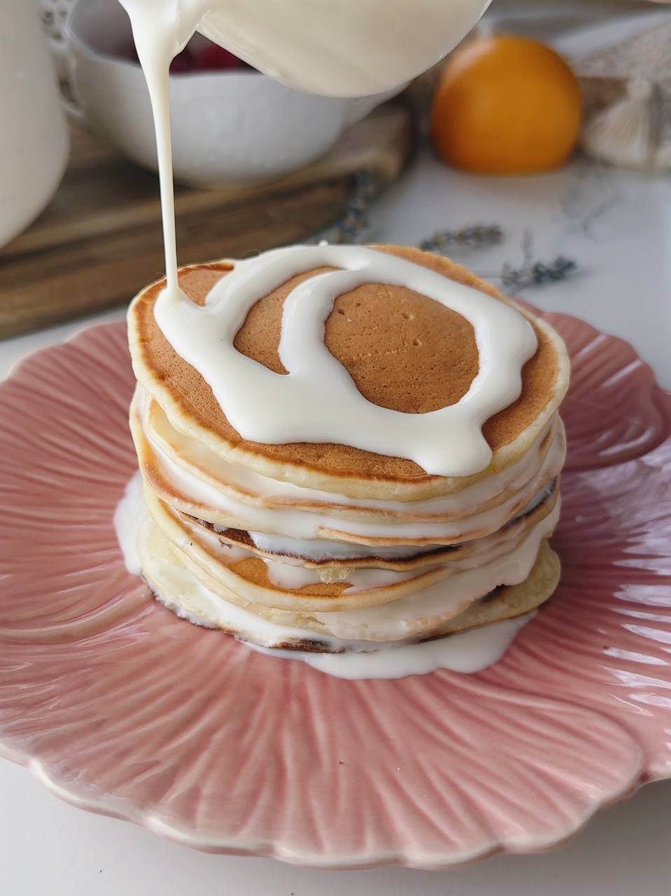 Creamy yogurt topping dripping over a stack of lemon yogurt pancakes