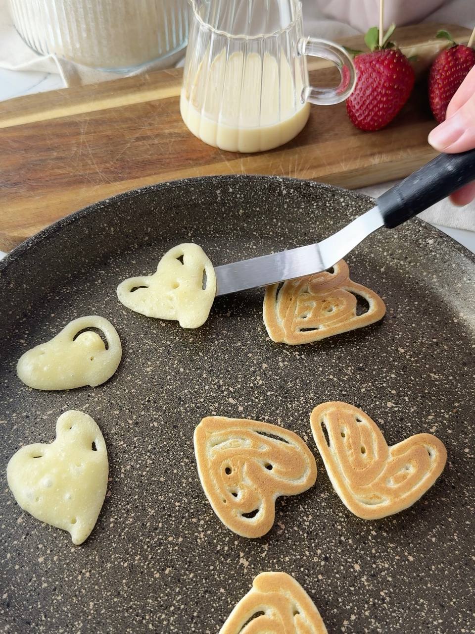Flipping heart shaped pancakes on a non-stick pan