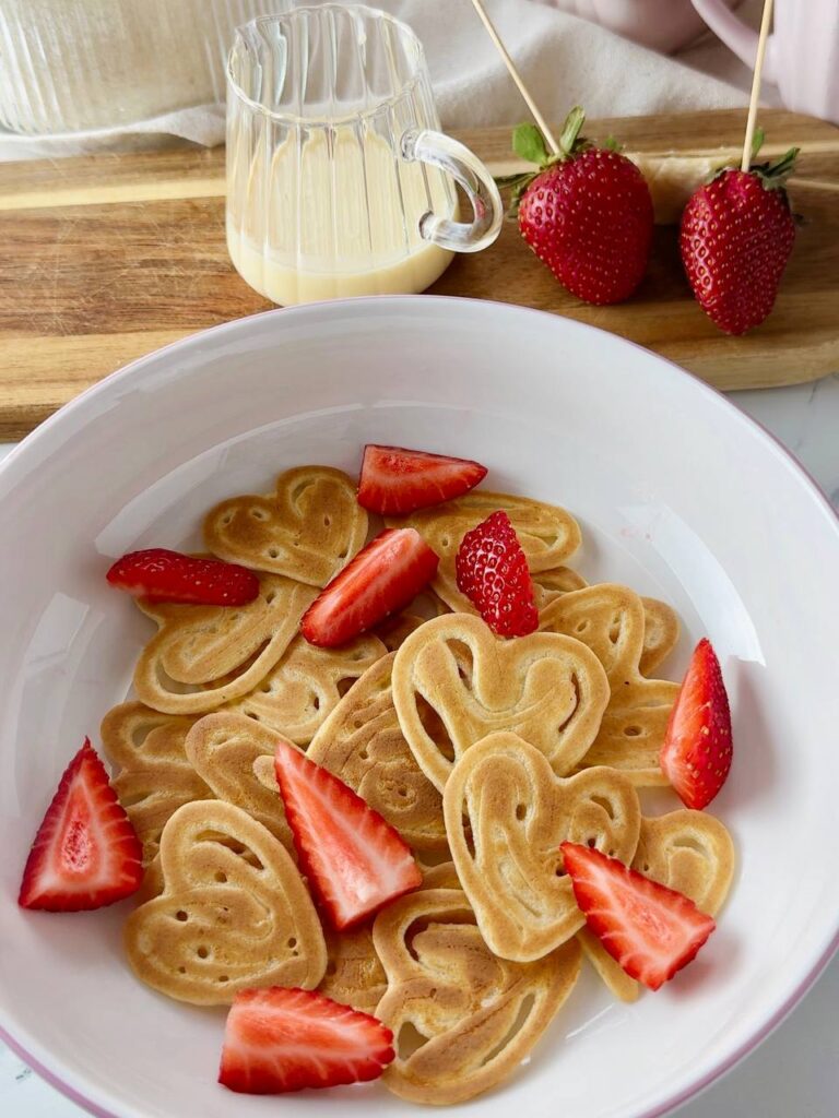 Heart shaped pancakes served with fresh strawberries