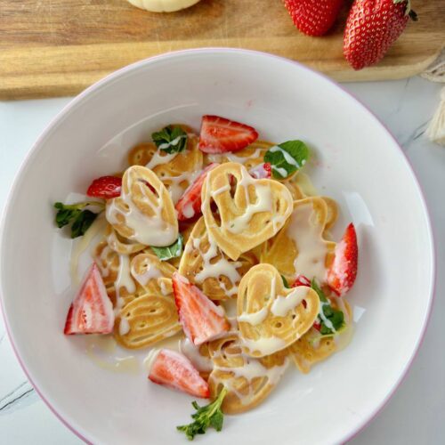 Heart shaped pancakes with strawberries, mint, and condensed milk sauce