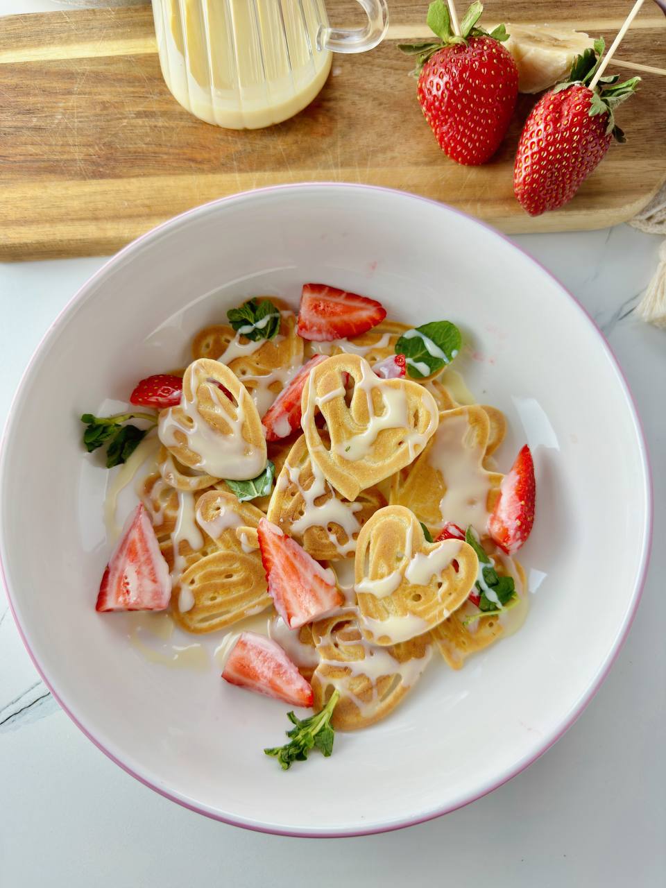 Heart shaped pancakes with strawberries, mint, and condensed milk sauce