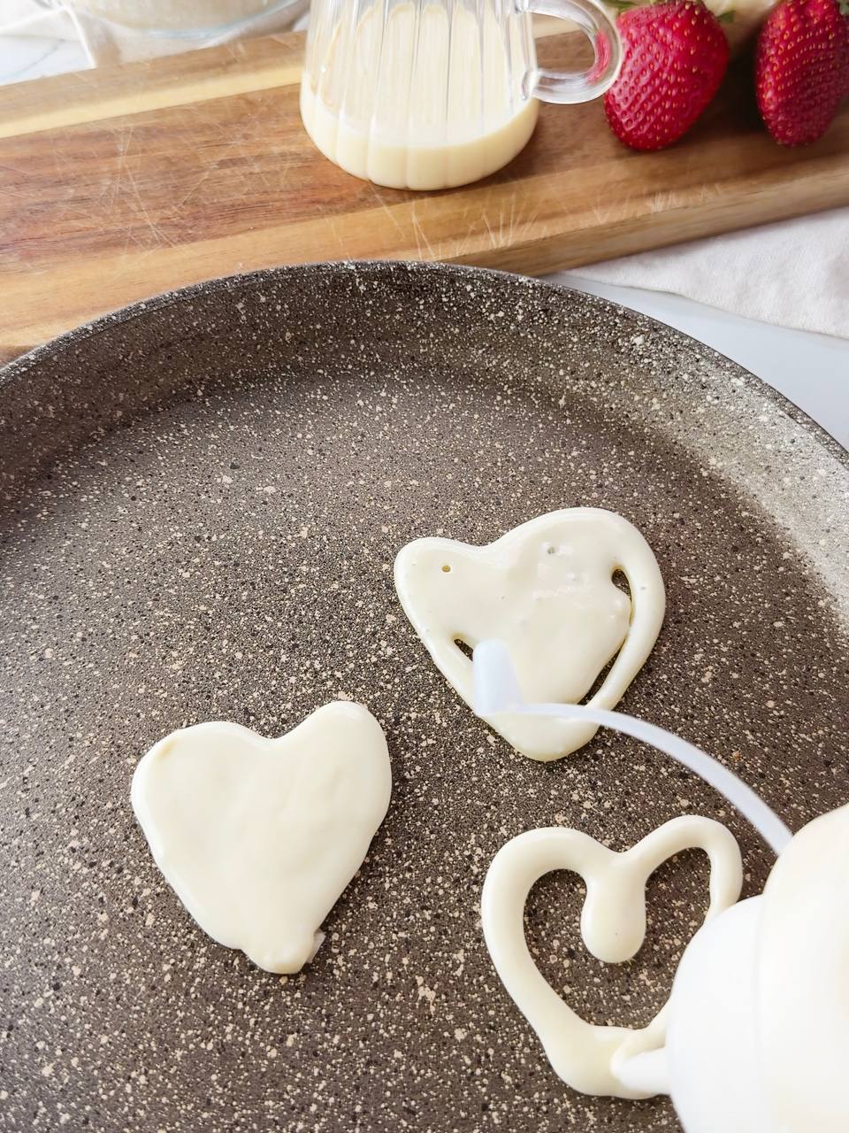 Making heart shaped pancakes on a pan using squeeze bottle