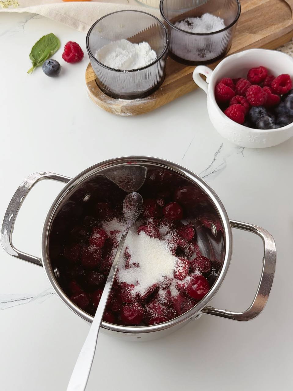 Frozen cherries cooking with sugar in a saucepan for galette filling