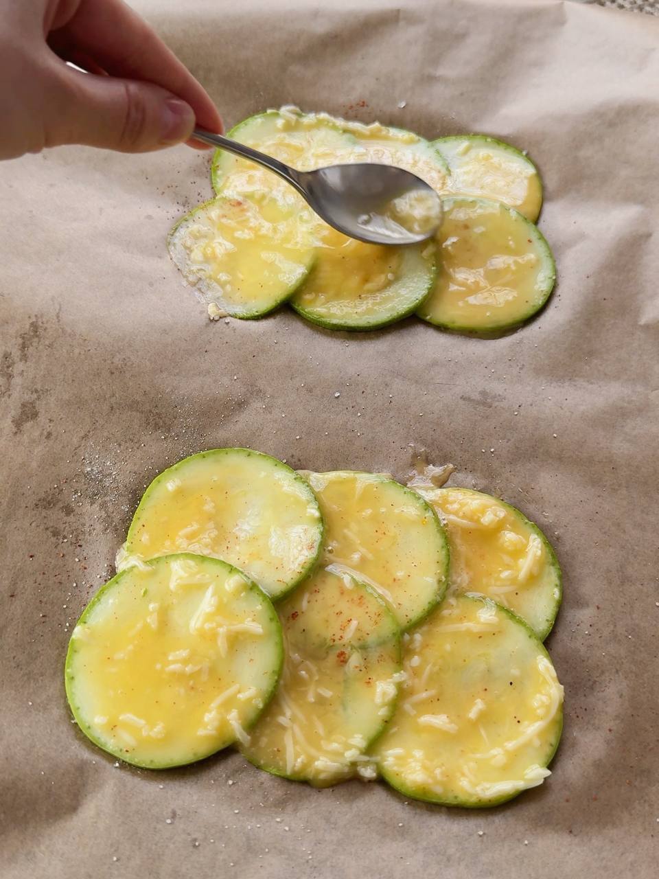 spreading egg and cheese mixture over layered zucchini slices
