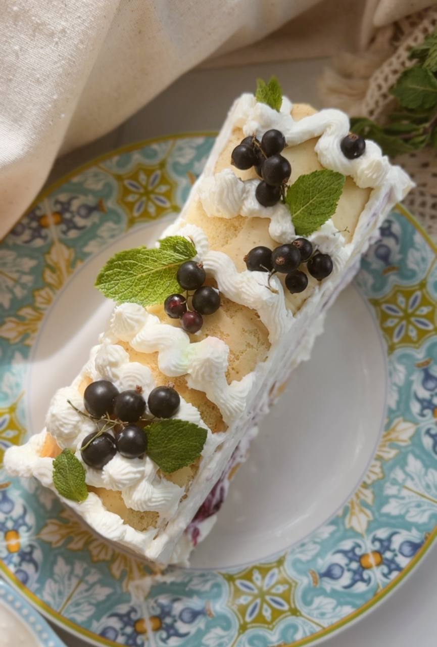 berry roll cake decorated with fresh blackcurrants and mint