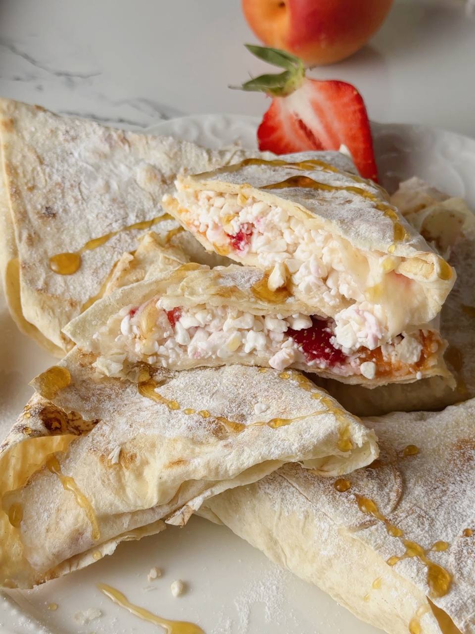 close up of a cottage cheese breakfast wrap with strawberry, banana, and apricot filling