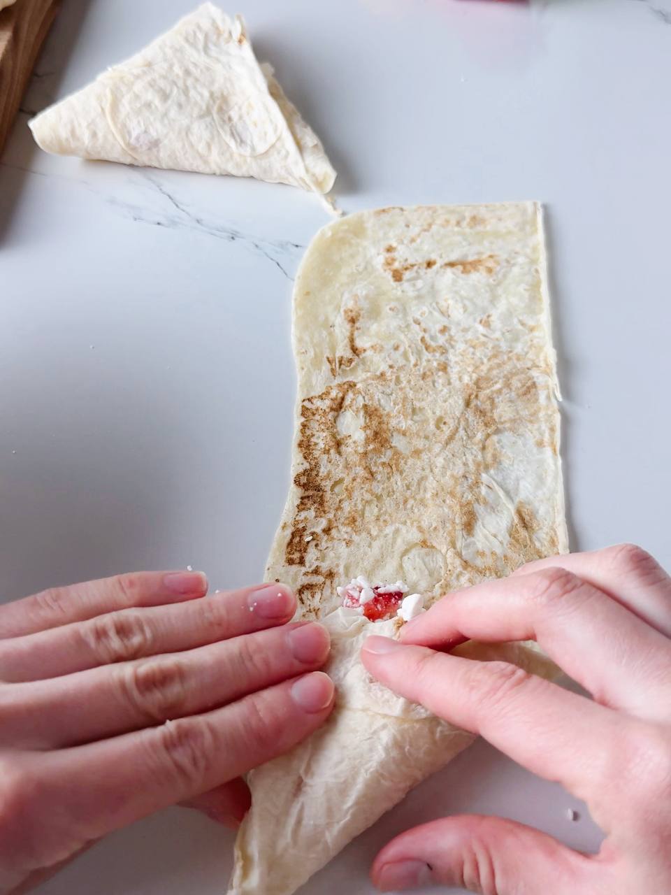 folding a lavash strip over the filling to form a triangle