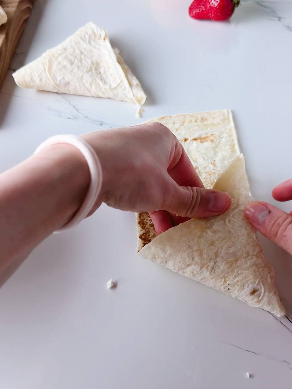 continuing to fold the wrap into a triangle shape