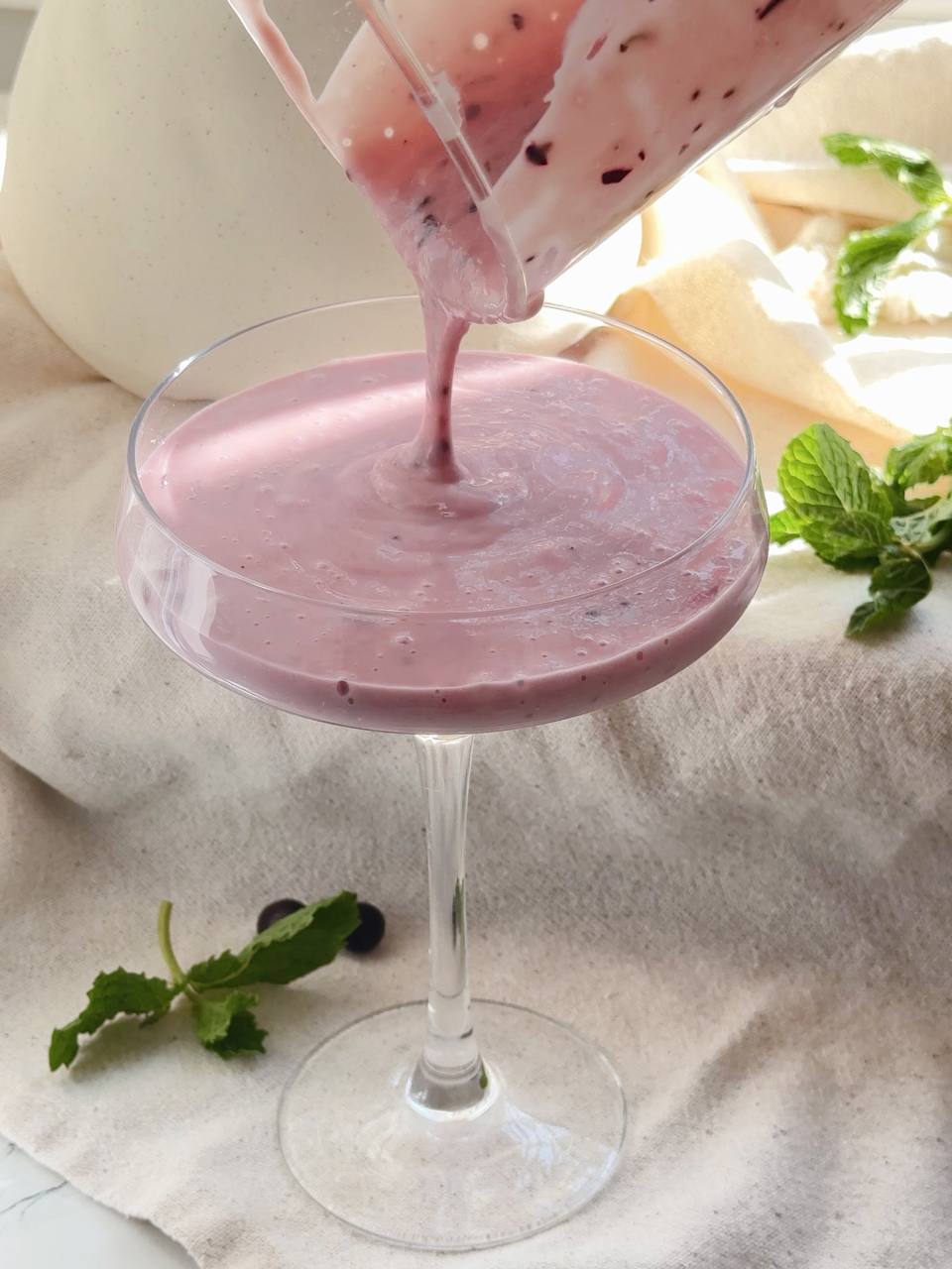 pouring the blackcurrant smoothie into a serving glass