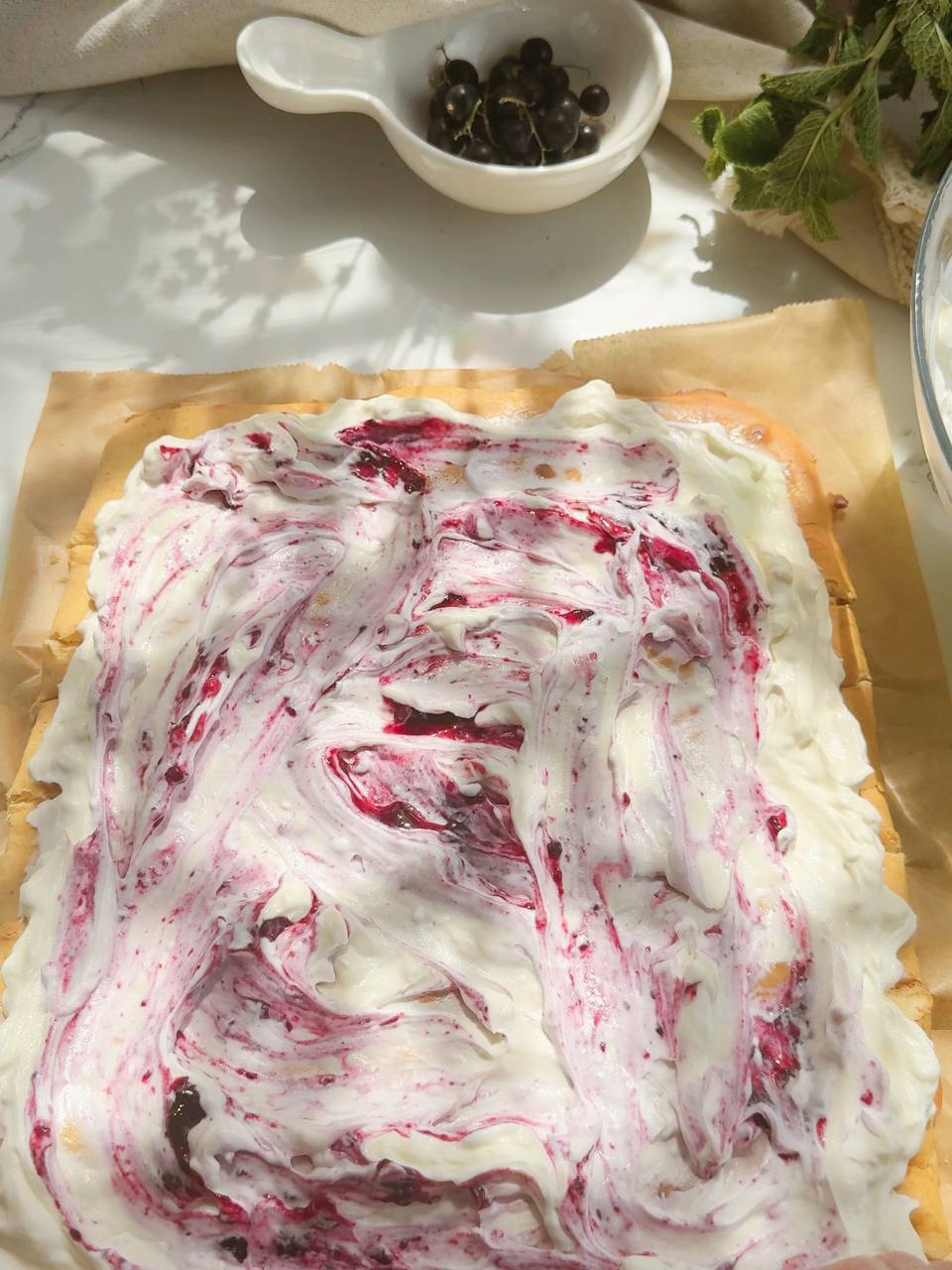 sponge cake covered with cream and blackcurrant jam