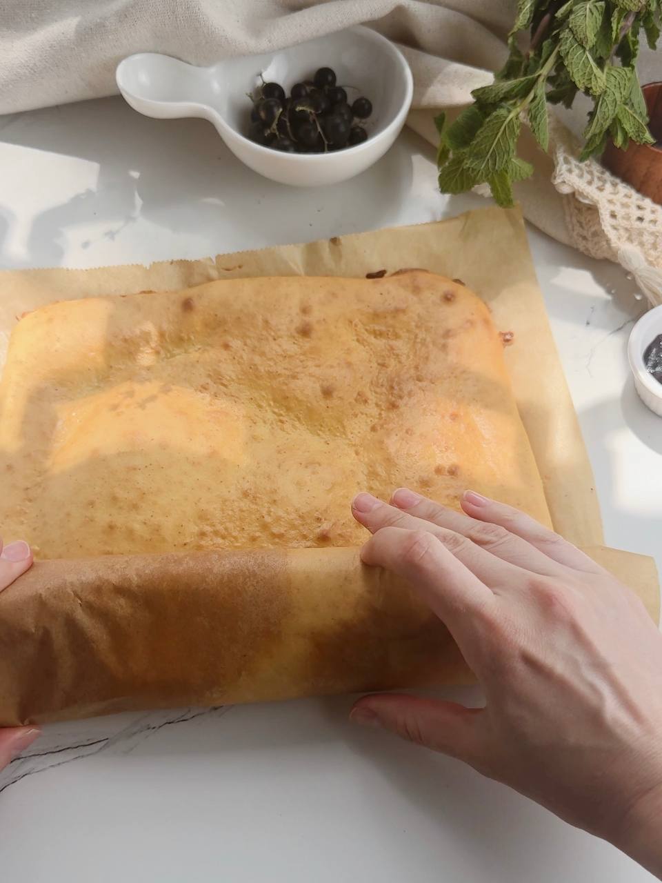 rolling the warm sponge cake with parchment paper
