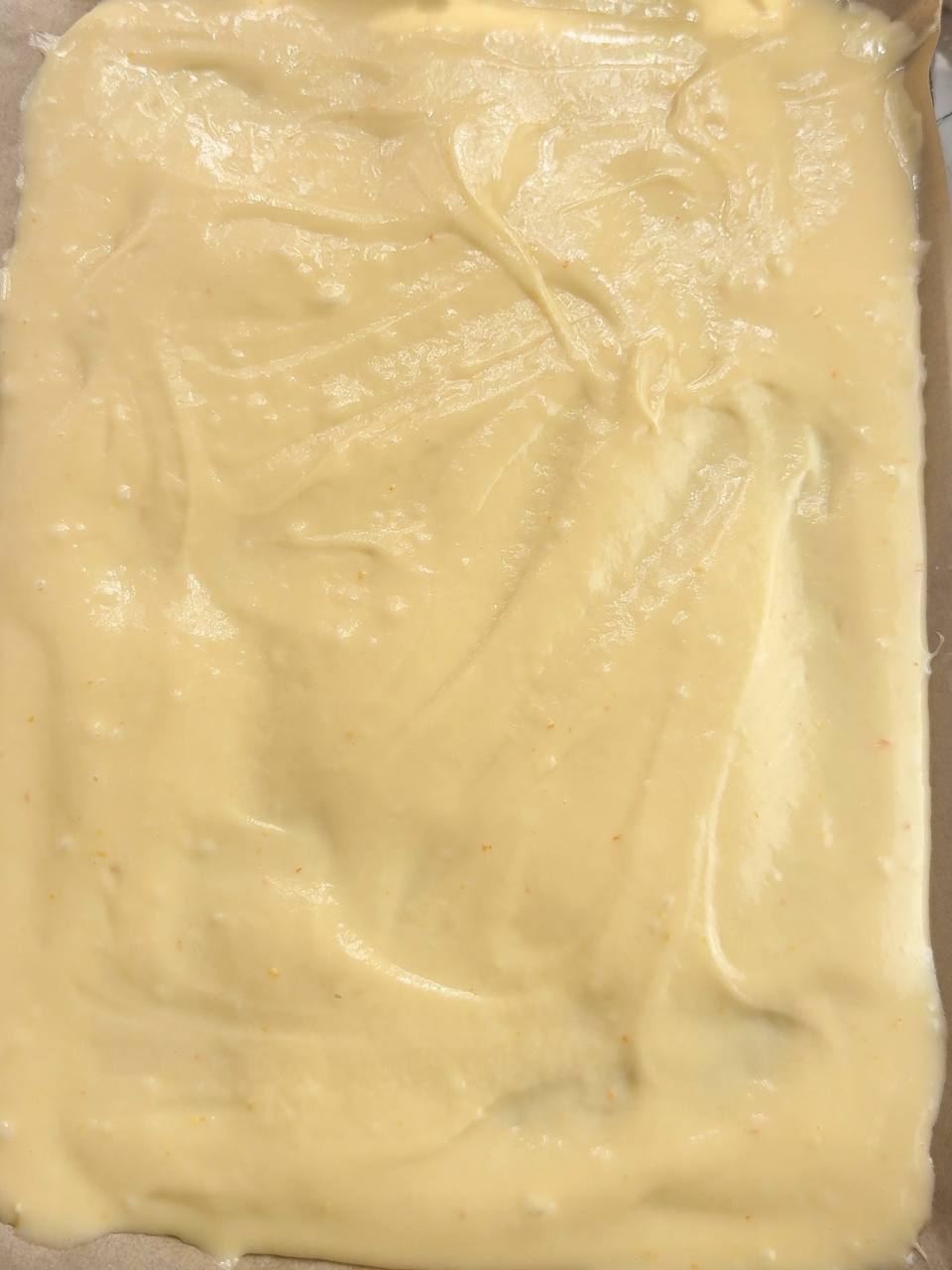 sponge cake batter spread evenly on a baking tray