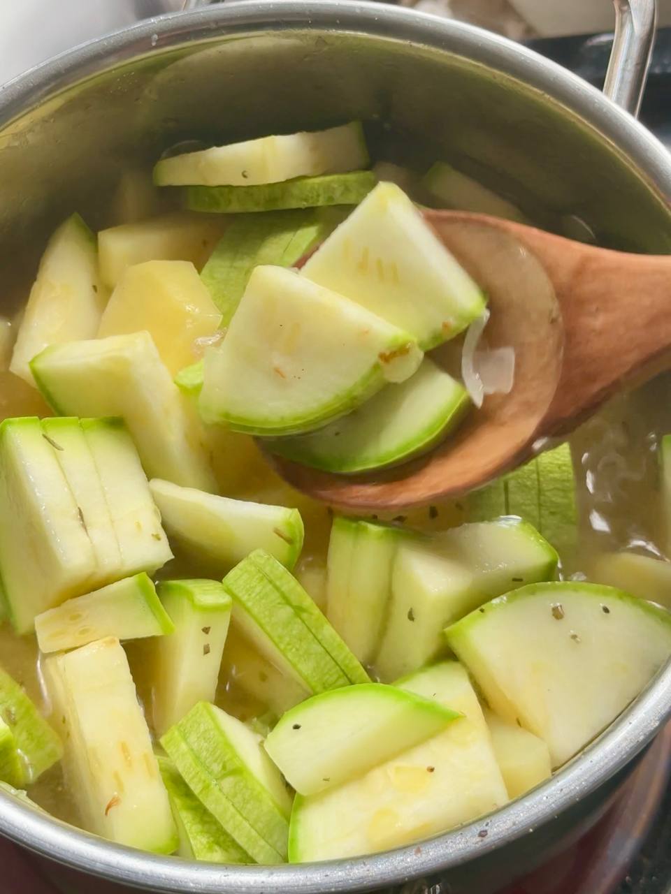 pouring vegetable broth into the zucchini soup