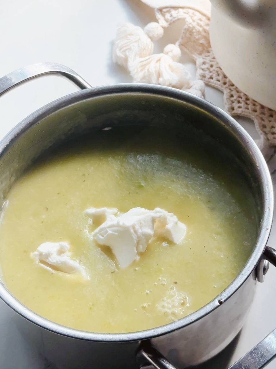 adding cream cheese to the zucchini soup before blending